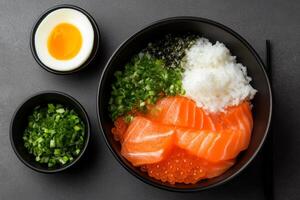 Fresh sashimi bowl with salmon, rice, and toppings served in a dark setting photo