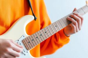 Person plays electric guitar in bright orange sweater against a light background photo