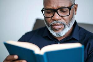 Man engaged in reading an interesting book while sitting comfortably in a chair at home during daylight hours photo