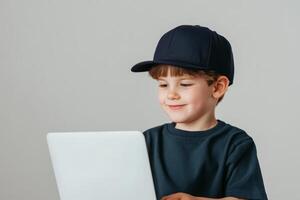 Young boy wearing a cap smiles while using a laptop in a bright indoor setting photo