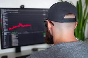 Man analyzes financial data on computer screen in modern workspace with indoor plants during daylight hours photo