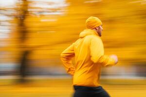 Runner in yellow gear moves through an autumn park with vibrant orange foliage during a brisk morning jog photo