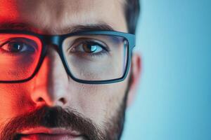 Close-up of a man with glasses showcasing well-defined facial features and captivating eyes under colorful lighting at dusk photo