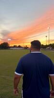 Sunset stroll at a soccer field with vibrant sky colors and player silhouette photo