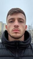 Young man poses for a close-up portrait in an urban environment during wintertime photo