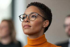 Engaged listener in a professional setting wearing glasses and an orange turtleneck photo