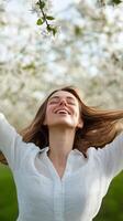 Joyful woman enjoying springtime in a blooming orchard with a bright smile and flowing hair photo