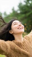 Young woman joyfully enjoying a sunny day outdoors with arms wide open in a natural setting photo