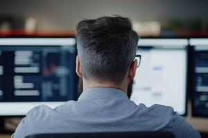Person working on multiple computer screens in a modern office setting during daytime photo