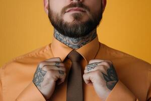 Man adjusting tie while wearing orange shirt and displaying tattoos against a yellow background photo