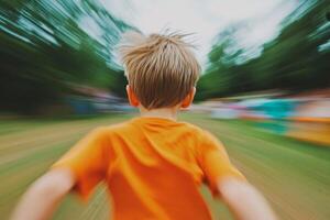 Child joyfully running in a vibrant orange shirt during an outdoor activity in a park on a cloudy day photo