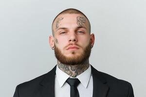 Confident man with tattoos wearing a suit and tie in a neutral studio setting photo