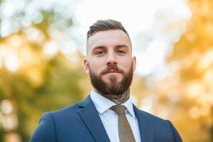 Confident man in a suit standing outdoors in a park during autumn with a warm golden background photo