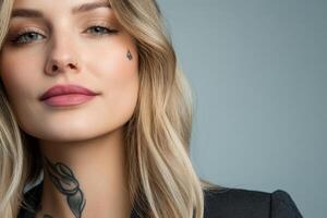 Close-up of a confident woman with a tattoo and soft makeup posing against a light backdrop photo
