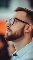 Engaged man in glasses reflects during a thoughtful moment at a crowded event in a modern venue photo