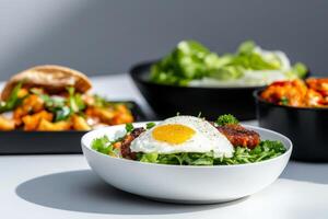 Fresh salad topped with a sunny side up egg and grilled chicken served with various sides in a bright setting photo