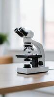 Laboratory microscope on a wooden table in a bright room with natural light during daytime photo