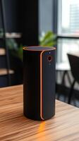 Modern black smart device with orange accents stands on a wooden table in a stylish interior setting photo