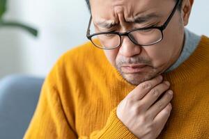 Man experiencing throat discomfort while sitting indoors in a cozy environment photo