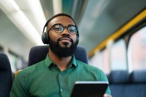 Young man enjoying music on a train while using a tablet, showcasing modern commuting experience photo