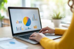 Person working on laptop analyzing data presented in graphs and charts during daytime at a bright, modern workspace photo