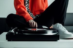 Sitting on a sofa, a person in an orange sweater enjoys playing vinyl records on a turntable photo