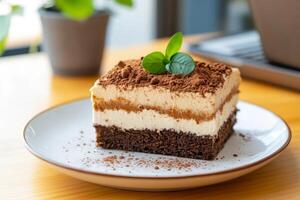 Tiramisu dessert served on a white plate with green garnishes at a cozy cafe during afternoon hours photo