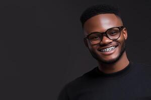 Young man with glasses smiling confidently against a dark background photo
