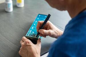 Man labeling compartments of his pill organizer with a permanent marker. Concept of organizing and personalizing medication management. High quality photo