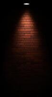 Single spotlight illuminating a textured red brick wall against a dark background photo