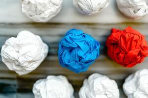 A vibrant row of colorful crumpled paper balls arranged neatly on a rustic wooden background, creating a playful and creative visual photo