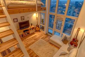 A cozy and stylish modern attic bedroom featuring wooden stairs, a comfortable bed, and a guitar, creating a warm and inviting atmosphere photo