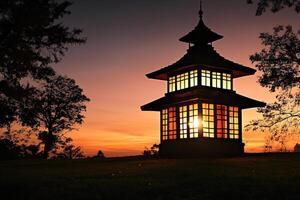 A lantern glowing softly in a garden during sunset, with a breathtaking sky in the background, creating a warm and tranquil atmosphere photo