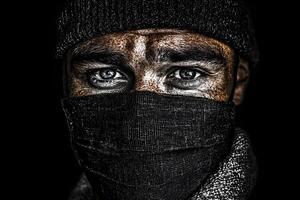 A striking close-up portrait of a man wearing a black mask, captured in a studio setting, highlighting his intense expression and the mysterious aura created by the mask photo