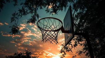 A striking image of a basketball hoop and net silhouetted against the vibrant colors of a sunset sky, capturing the essence of outdoor sports and evening tranquility photo