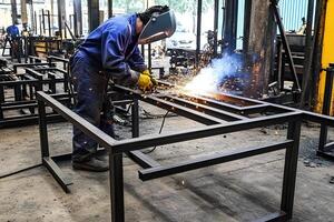 Industrial worker welding a steel structure at a construction site, showcasing metalwork and manufacturing in an industrial environment photo