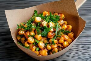 Roasted corn kernels with parsley in a paper bowl photo