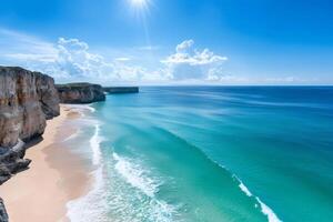 Turquoise ocean waves gently rolling onto a deserted sandy beach below high cliffs in Sagres, Portugal photo