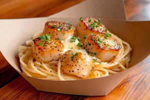 Seared scallops resting on a bed of spaghetti with butter and chives photo