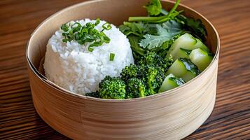 Steamed rice, broccoli, cucumber and coriander in bamboo box on wooden table photo