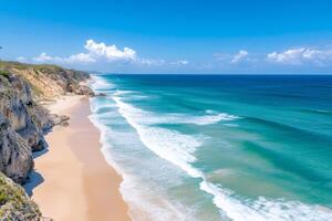 Ocean waves crashing on a pristine sandy beach next to a rocky cliff in Portugal photo