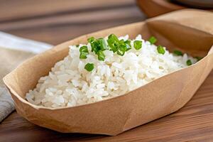 Steamed rice garnished with chopped chives served in a takeaway container photo