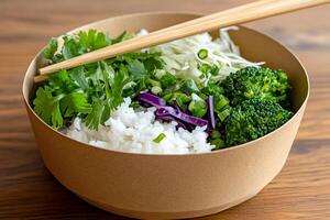 Chopsticks resting on a bowl of rice with coriander, broccoli and red cabbage photo