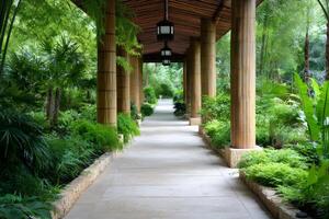 Covered walkway with bamboo columns traversing lush tropical garden photo
