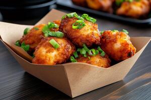 Crispy fried chicken nuggets garnished with chopped green onions in a brown cardboard takeout container photo