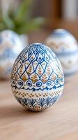 Easter egg decorated with blue and gold ornaments standing on wooden table photo