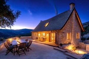Charming stone cottage illuminating the night with warm lights under starry sky photo