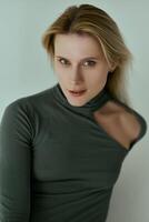 Young beautiful ballerina in a black bodysuit posing on a studio photo