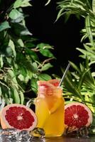 Detox refreshing cocktail from grapefruit and rosemary with ice. Summer drink. Grapefruit lemonade in a glass jar on a dark background. Mason jar photo