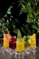 Variety of lemonade in mason jars with berries and fruits. summer lemonade in a glass with ice on a dark background photo